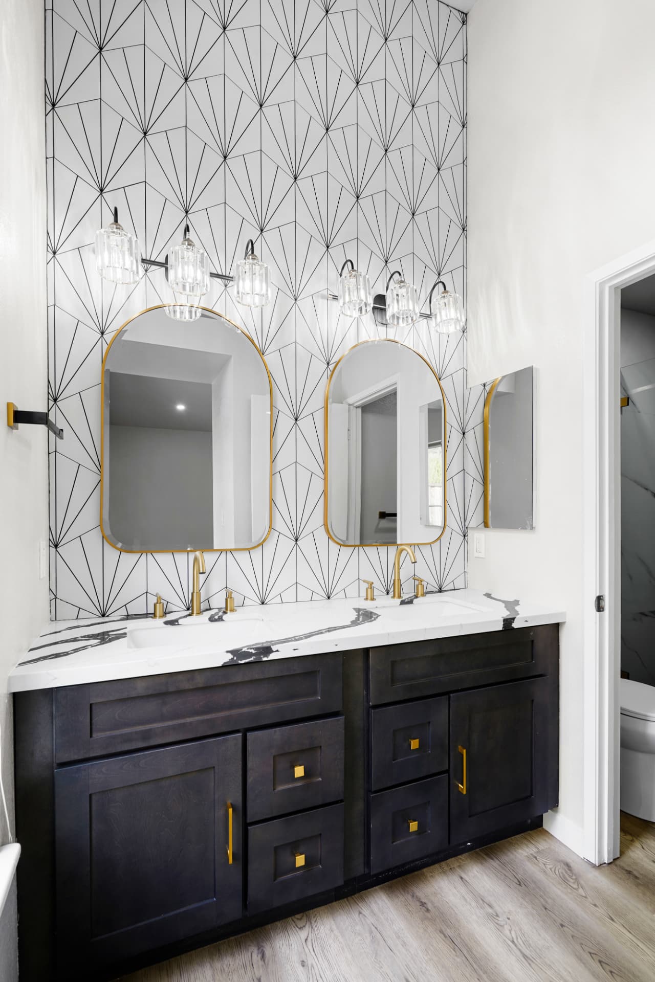 Spa-style bathroom remodel with black double vanity and geometric tile wall